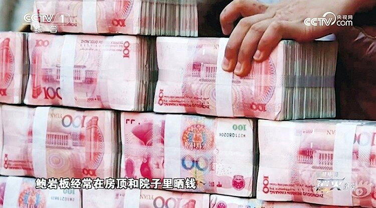 电骗头目手握巨额不义之财,常在房顶里摊开钞票晒太阳,成为当地一景。(视频截屏)