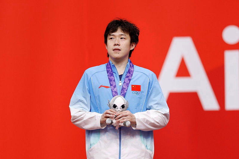 在名古屋亚运乒乓球项目男子单打决赛中,王楚钦负于林诗栋,获得银牌。图为王楚钦在颁...