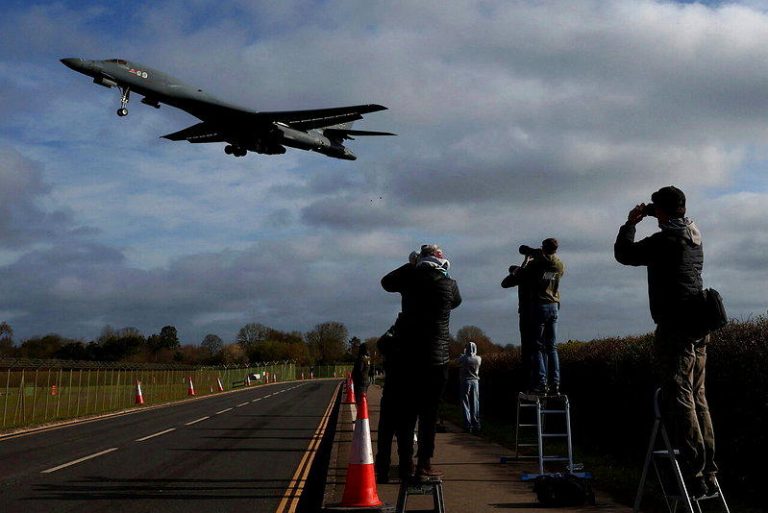 美国空军一架B-1轰炸机3月17日准备降落英国格洛斯特郡费尔福空军基地，民众举起...