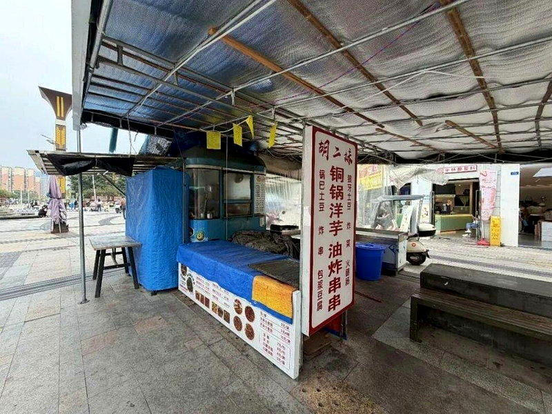 胡二妹摊位招牌依然挂着,上面写着「胡二妹 铜锅洋芋 油炸串串」。(取材自华商报大...